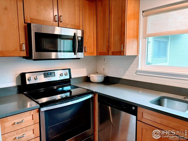 kitchen with backsplash, brown cabinets, and appliances with stainless steel finishes