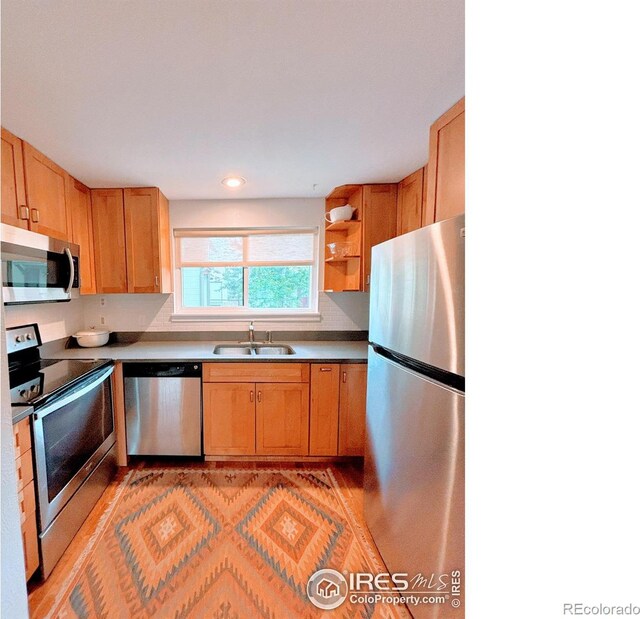 kitchen with appliances with stainless steel finishes, open shelves, and a sink