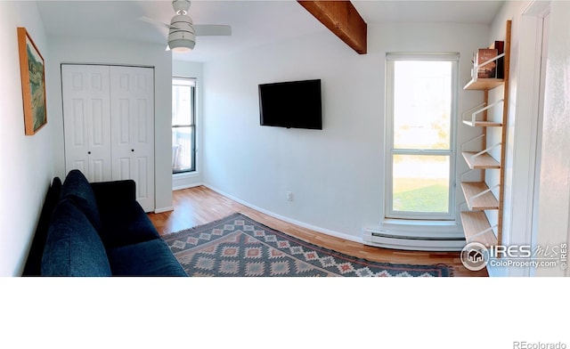 living room featuring beamed ceiling, baseboards, wood finished floors, and a ceiling fan