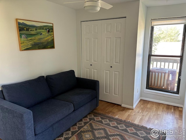 living area with ceiling fan, baseboards, and wood finished floors