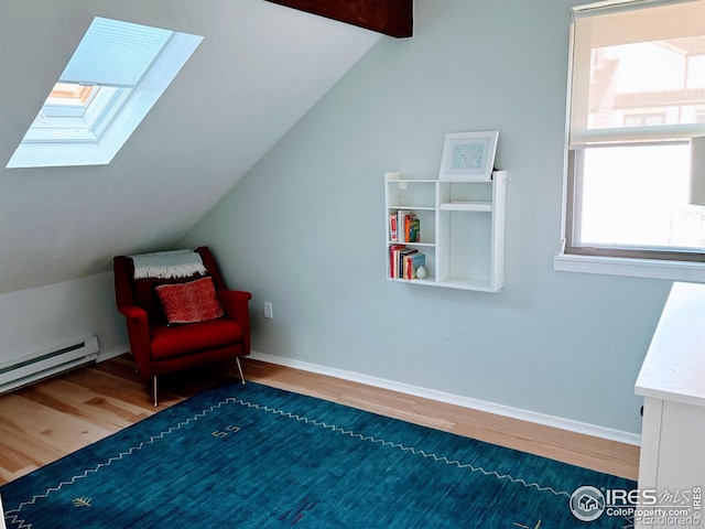 sitting room with lofted ceiling with skylight, a baseboard heating unit, baseboards, and wood finished floors