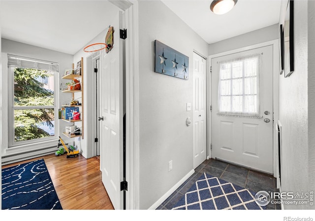 doorway to outside featuring dark wood finished floors, baseboards, and a baseboard radiator