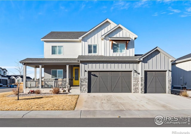 modern farmhouse with an attached garage, covered porch, stone siding, concrete driveway, and board and batten siding