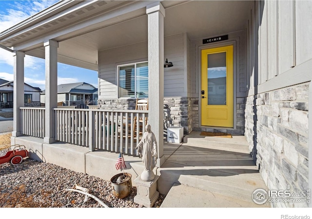 view of exterior entry with covered porch and stone siding