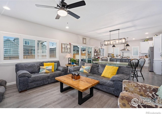 living area featuring a ceiling fan, recessed lighting, and light wood-style flooring