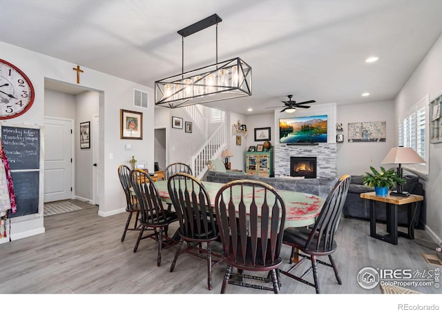 dining space with baseboards, stairway, a tiled fireplace, and wood finished floors