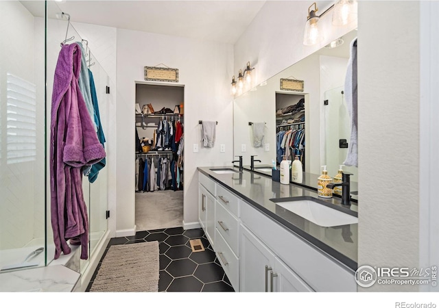 full bath with double vanity, a sink, a walk in closet, and a shower stall