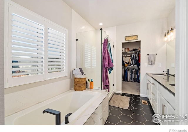 full bath featuring a walk in closet, a garden tub, recessed lighting, vanity, and tile patterned floors