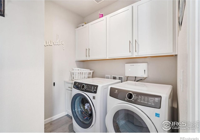 laundry area with light wood-style floors, washer and dryer, cabinet space, and baseboards