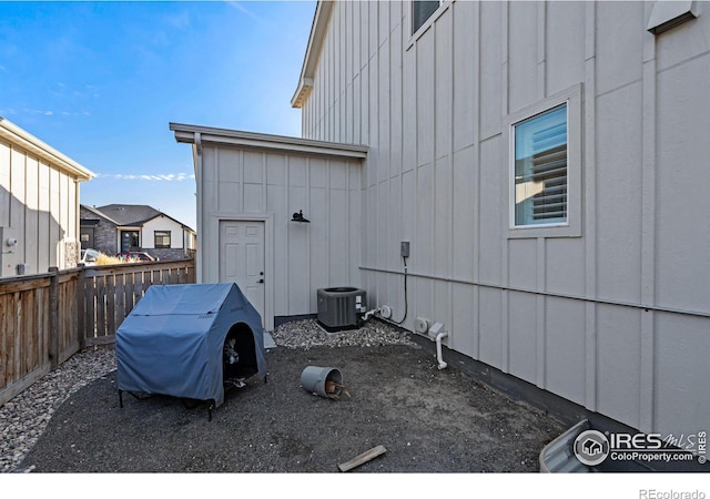 view of property exterior featuring board and batten siding, cooling unit, and fence