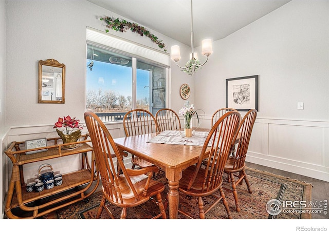 dining space with a wainscoted wall, a decorative wall, and a notable chandelier