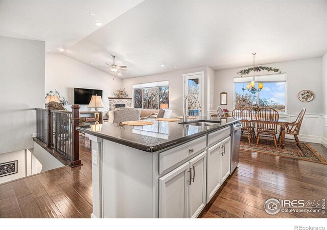 kitchen featuring stainless steel dishwasher, dark wood-style floors, vaulted ceiling, and a sink