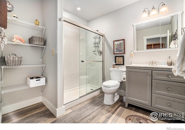 full bathroom with baseboards, toilet, wood finished floors, vanity, and a shower stall