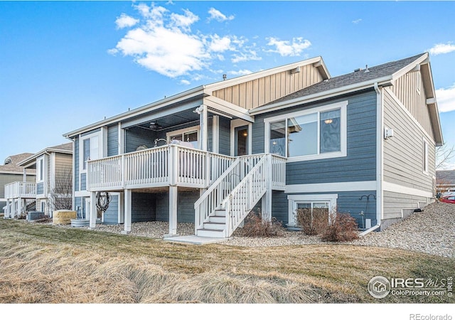 back of property with a yard, a deck, and stairs