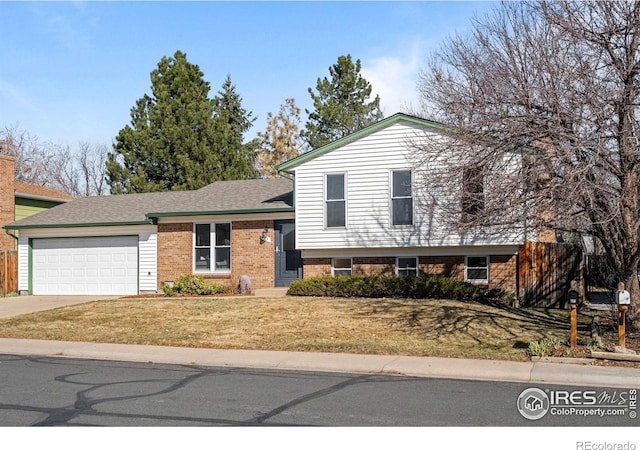 split level home featuring a garage, brick siding, driveway, roof with shingles, and a front yard