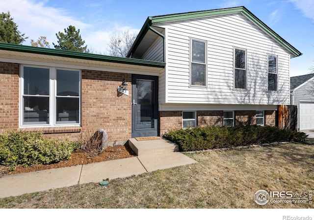 split level home featuring a garage and brick siding