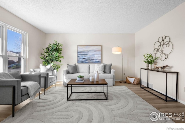 living area with a textured ceiling, baseboards, and wood finished floors