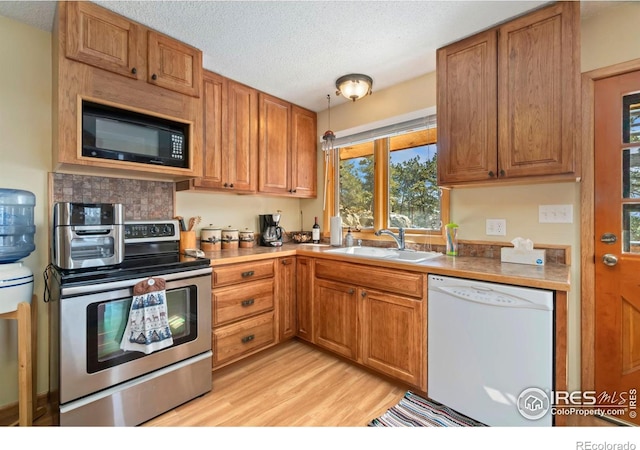 kitchen with light wood-style floors, a sink, black microwave, dishwasher, and stainless steel electric range