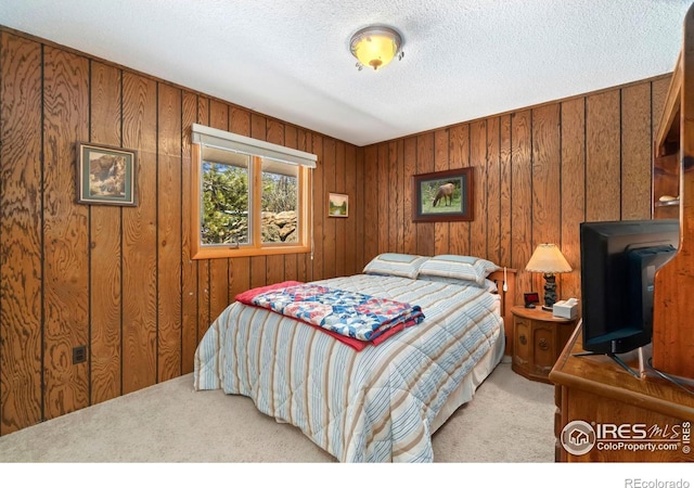 bedroom with carpet, wooden walls, and a textured ceiling