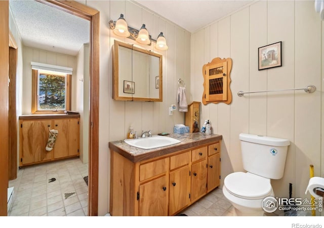 bathroom with toilet, tile patterned floors, a textured ceiling, and vanity