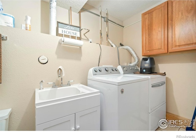 laundry area with a textured ceiling, washing machine and clothes dryer, and cabinet space