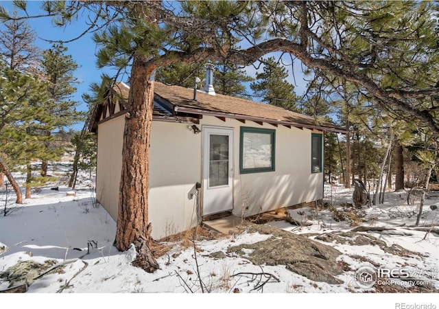snow covered property featuring stucco siding