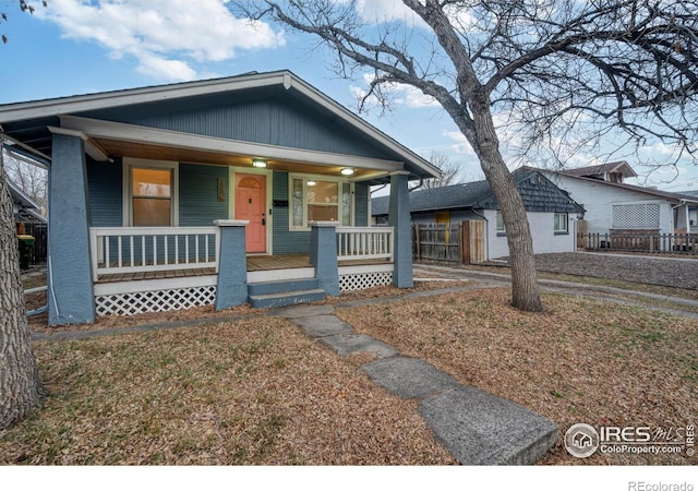 bungalow-style home featuring a porch and fence