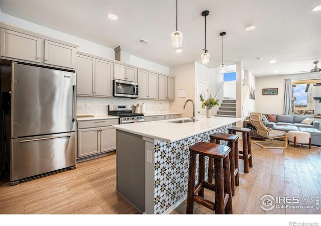 kitchen with appliances with stainless steel finishes, gray cabinets, a sink, and open floor plan