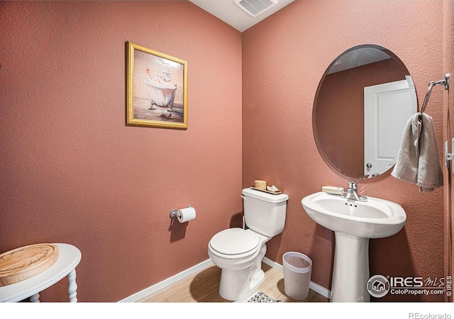 bathroom with toilet, baseboards, visible vents, and wood finished floors