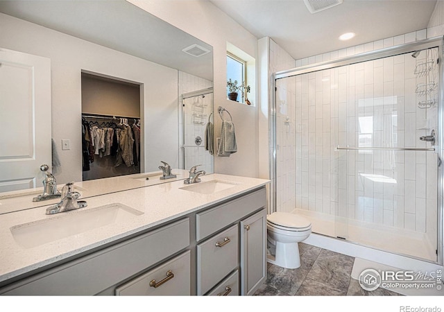 bathroom with toilet, a sink, visible vents, and a shower stall