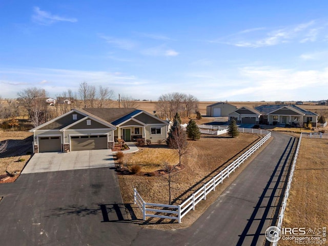 view of front of property featuring driveway, stone siding, a garage, and fence