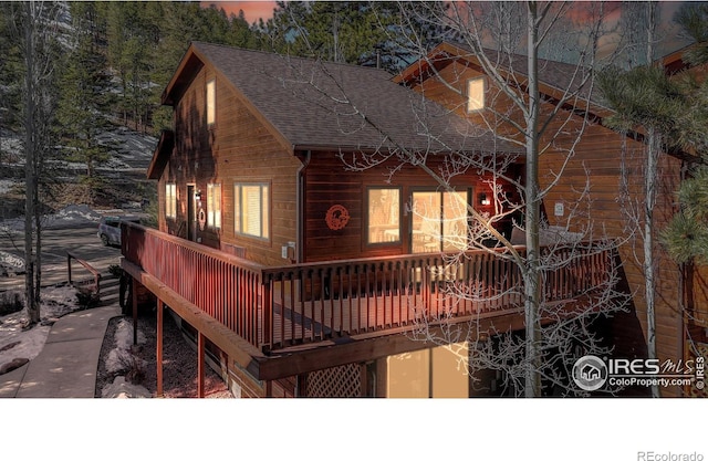 view of front facade featuring a shingled roof and a deck