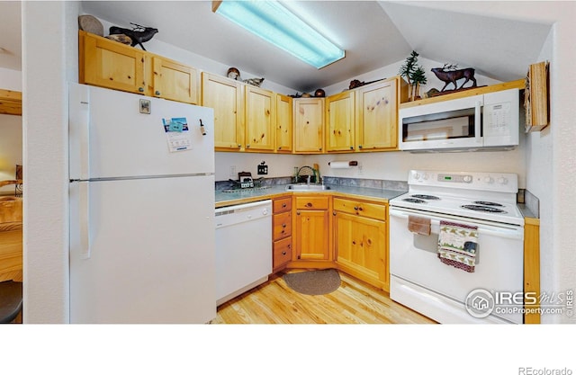 kitchen featuring light brown cabinets, white appliances, a sink, light wood-style floors, and vaulted ceiling