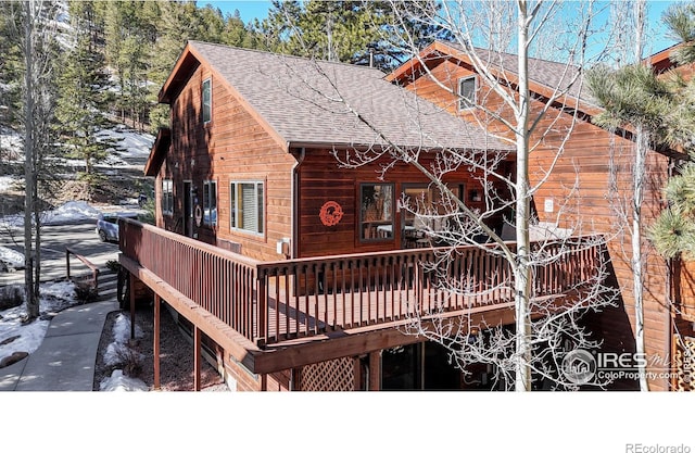 rear view of house featuring a shingled roof and a deck