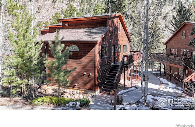 exterior space with stairway and roof with shingles