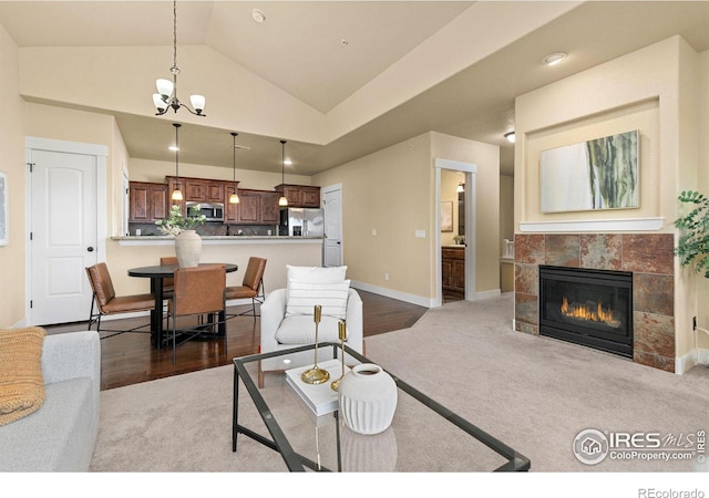 living area with a fireplace, baseboards, a notable chandelier, and carpet flooring