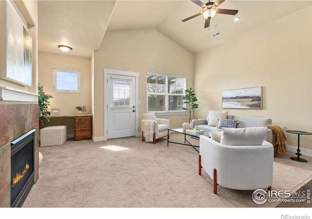 carpeted living area with high vaulted ceiling, baseboards, a ceiling fan, and a tiled fireplace