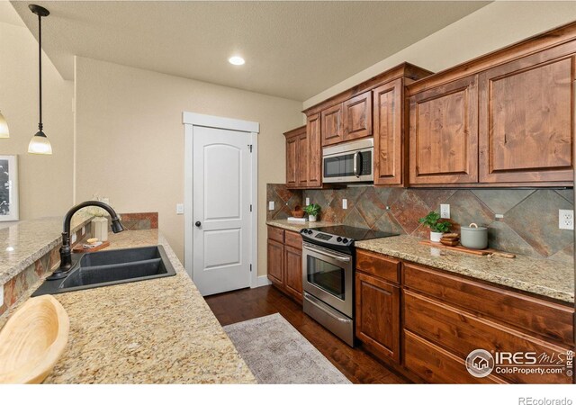 5850 Dripping Rock Ln Unit D201, Fort Collins, CO 80528 - kitchen with stainless steel appliances, a sink, brown cabinets, tasteful backsplash, and dark wood finished floors