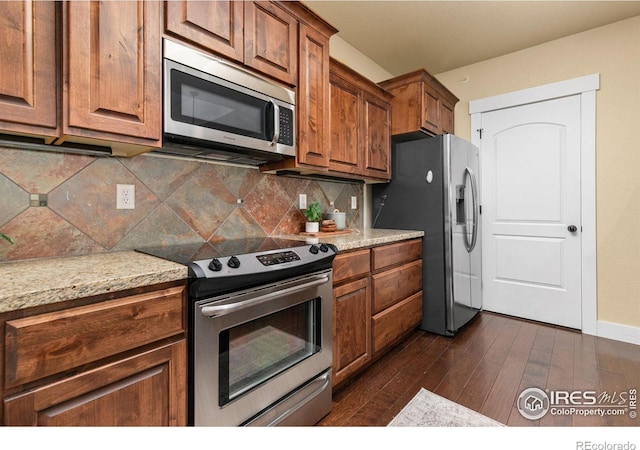 5850 Dripping Rock Ln Unit D201, Fort Collins, CO 80528 - kitchen with baseboards, brown cabinetry, dark wood-style floors, stainless steel appliances, and backsplash