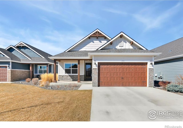 craftsman house featuring concrete driveway, stone siding, an attached garage, board and batten siding, and a front yard