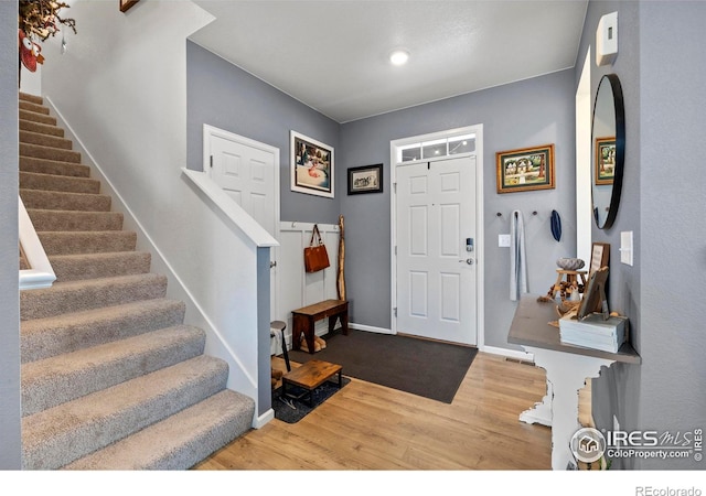 entrance foyer with stairs, wood finished floors, and baseboards