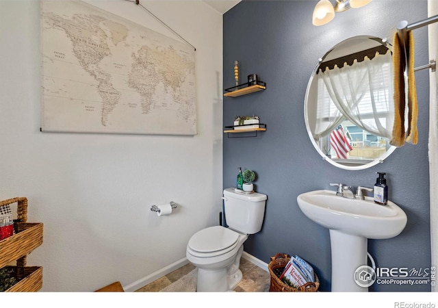 half bathroom featuring baseboards and toilet