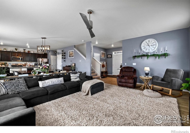 living room featuring a chandelier, stairway, and wood finished floors