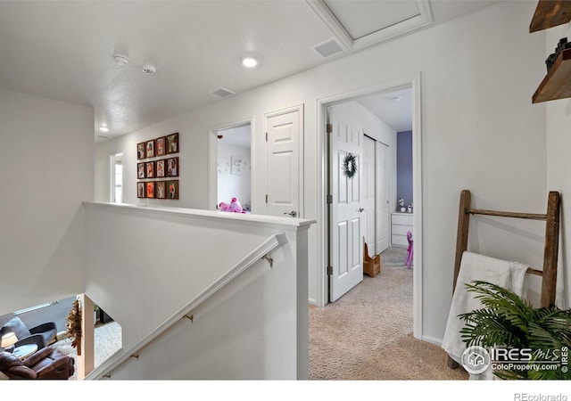 hall with recessed lighting, visible vents, light colored carpet, and an upstairs landing