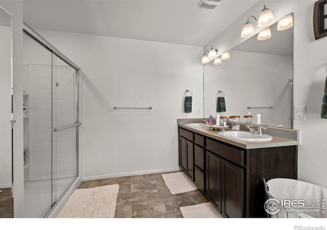 bathroom with a stall shower, stone finish floor, a sink, and double vanity