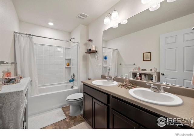 full bathroom featuring toilet, double vanity, visible vents, and a sink