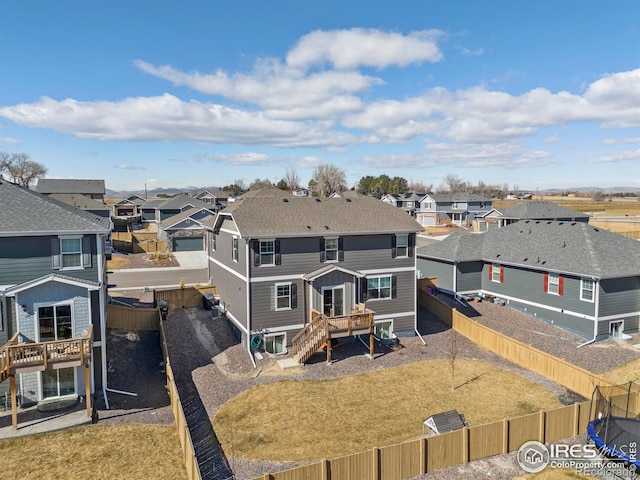 back of property with gravel driveway, a fenced backyard, a residential view, and a yard