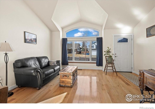 living area with lofted ceiling, wood finished floors, and baseboards