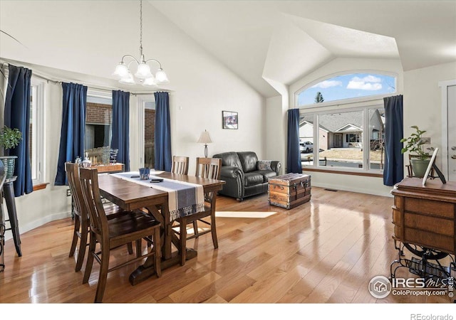 dining room featuring light wood finished floors, baseboards, visible vents, an inviting chandelier, and high vaulted ceiling