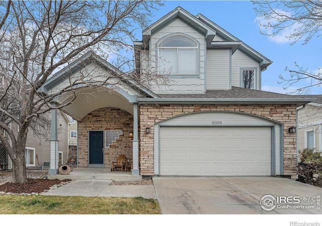 traditional-style home with a garage, concrete driveway, roof with shingles, and stone siding